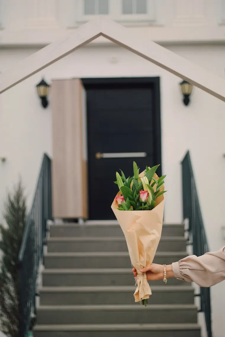 Hand Holding Bouquet in front of House